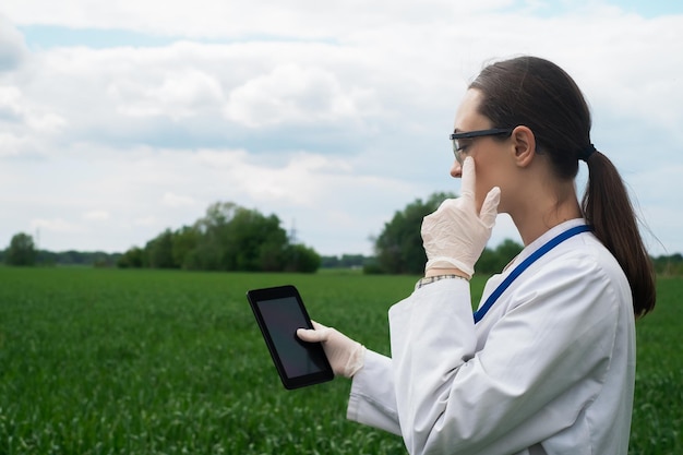 Foto uma agrônoma de jaleco branco verifica o crescimento das plantas no campo uma bióloga no