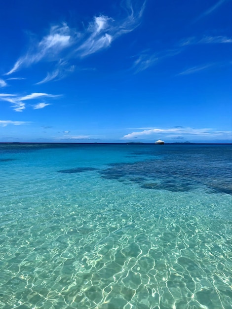 Uma água límpida, límpida e azul com um barco ao longe.