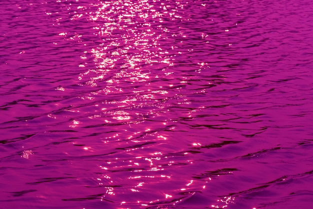 Uma água roxa com o sol brilhando sobre ela