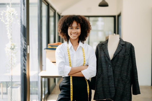 Foto uma alfaiate africana a trabalhar em roupas num atelier de alfaiataria uma bela jovem designer de moda sorri e depois do sucesso no estúdio