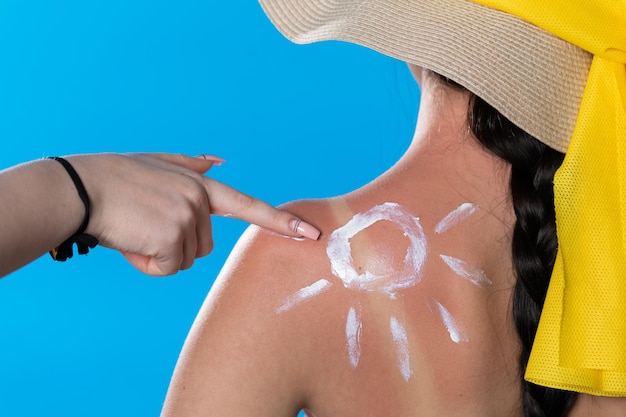Foto uma amiga lubrifica as costas de suas amigas com um protetor solar enquanto faz o símbolo do sol
