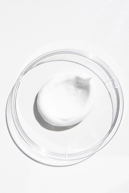Uma amostra de um produto cosmético branco em um recipiente em uma vista superior de fundo de madeira