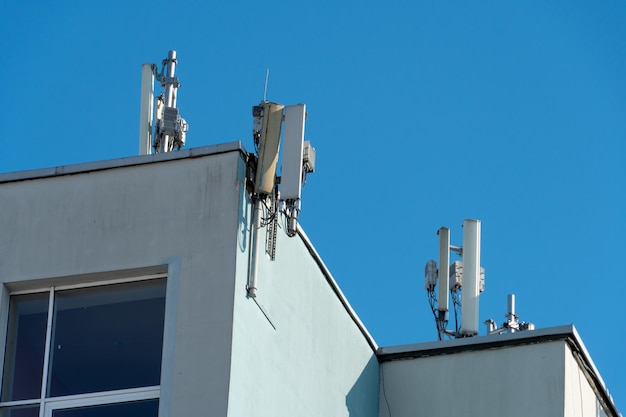 Uma antena de comunicação celular instalada no telhado de um edifício alto contra um fundo de céu azul Equipamento de telecomunicações de rede de rádio 5G com módulos de rádio e antenas inteligentes