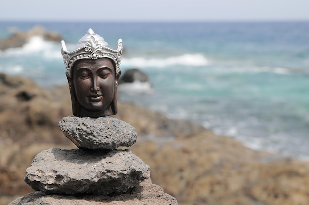 Uma antiga estátua de Buda cinza perto do oceano