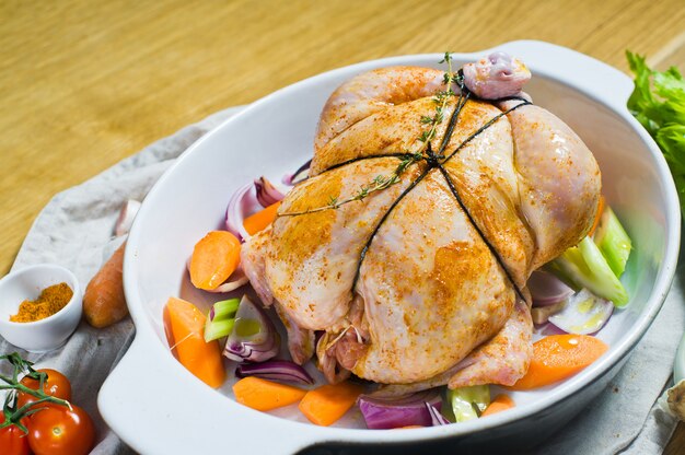 Uma assadeira com um pedaço de frango cru nas especiarias.