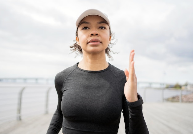 Uma atleta feminina corre faz um treino na rua em roupas esportivas e um relógio de fitness na mão
