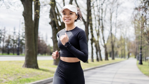 Uma atleta feminina corre faz um treino na rua em roupas esportivas e um relógio de fitness na mão