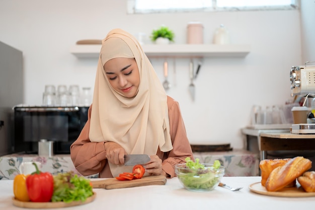 Uma atraente mulher muçulmana asiática ou dona de casa de hijab está preparando comida em uma cozinha