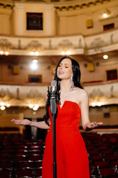 Foto uma atriz luxuosa em um vestido vermelho canta no palco com um microfone em suas mãos