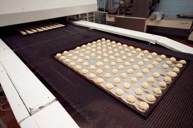 Uma bandeja de biscoitos prontos é retirada da esteira rolante na padaria