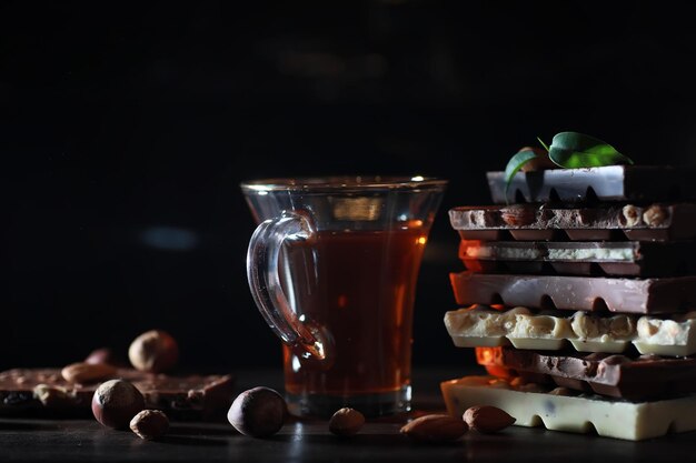 Uma barra de chocolate ao leite. Chocolate de leite caseiro com amêndoas e morangos secos. Pedaços de chocolate ao leite. Barra de chocolate ao leite sem etiqueta. Conjunto de chocolate com chá.