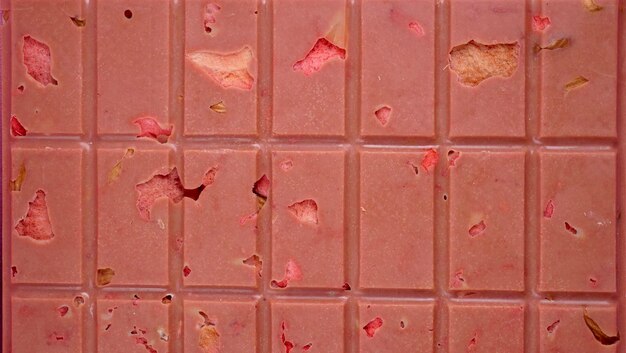 Uma barra de chocolate rosa ruby com morangos e amêndoas liofilizadas em close-up uma sobremesa saudável