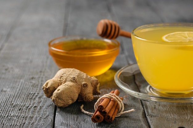 Uma bebida de gengibre, mel e frutas cítricas para fortalecer o sistema imunológico na mesa de madeira preta.