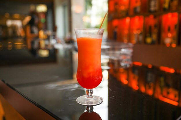 Uma bebida vermelha em um bar com um bar ao fundo