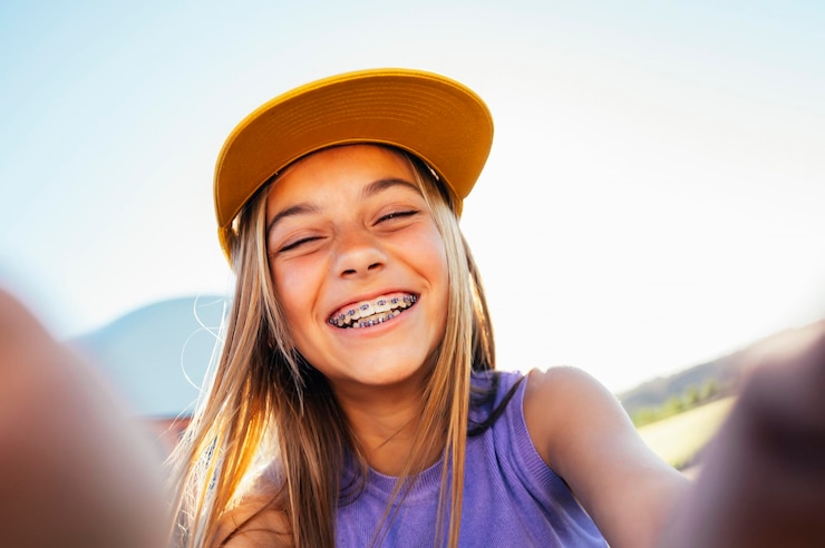 Foto uma bela adolescente a tirar selfies com um boné amarelo e um suporte nos dentes.
