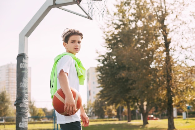 Uma bela adolescente tem uma bola de basquete nas mãos e olha para a câmera.