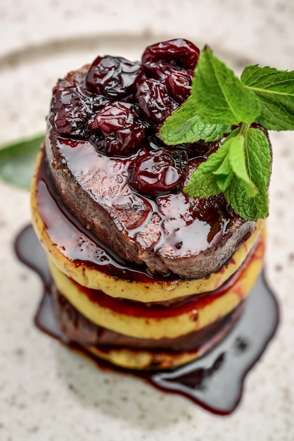 Uma bela apresentação de carne frita com maçã, alecrim e molho de cereja