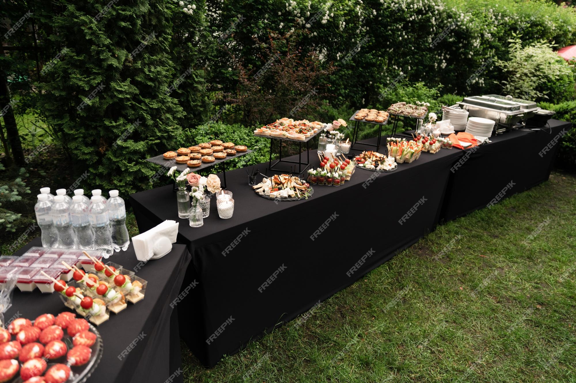 Uma bela decoração da mesa de buffet de casamento ao ar livre com doces,  flores frescas em porta-copos de madeira, uma abundância de doces em  porta-copos de madeira., recepção de buffet na