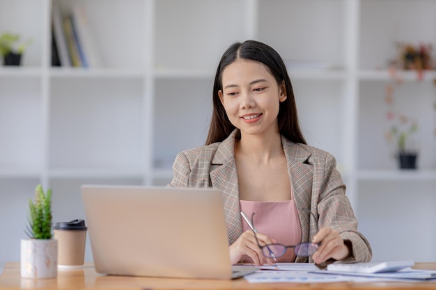 Uma bela empresária asiática sentada em seu escritório particular ela está verificando os documentos financeiros da empresa ela é uma executiva feminina de uma empresa startup Conceito de gestão financeira