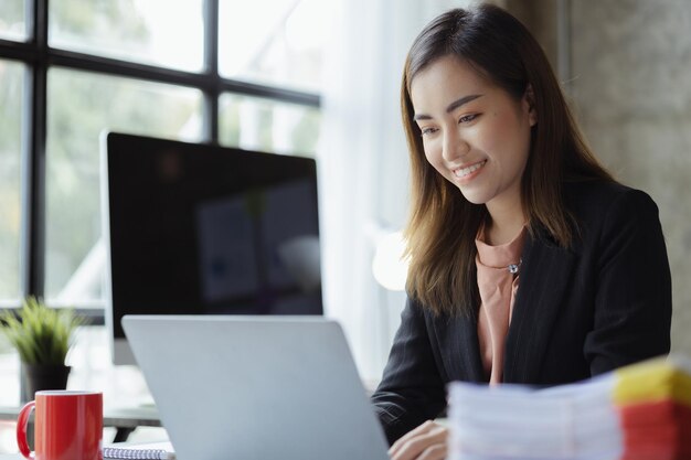 Uma bela empresária asiática sentada em seu escritório particular ela está verificando os documentos financeiros da empresa ela é uma executiva feminina de uma empresa startup Conceito de gestão financeira