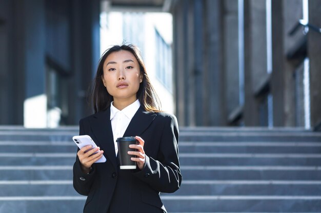 Uma bela estudante asiática usa o telefone perto do campus universitário