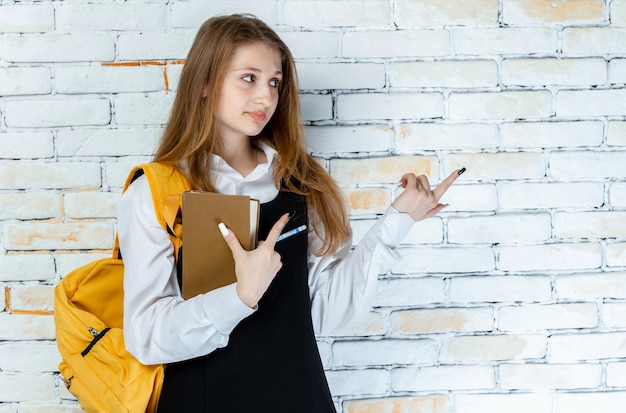 Uma bela estudante de uniforme fica em um fundo branco e olhando para o lado direito Foto de alta qualidade