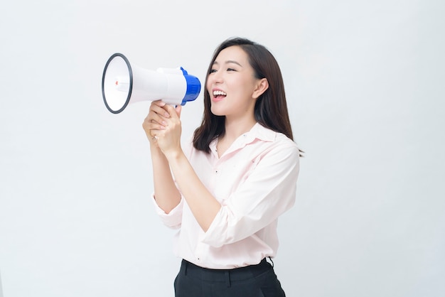 Uma bela jovem asiática está anunciando por megafone em fundo branco