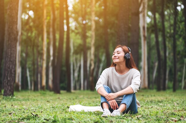 Uma bela jovem asiática gosta de ouvir música com fone de ouvido com sentimento feliz e relaxado no parque