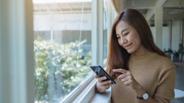 Uma bela jovem asiática segurando e usando telefone celular