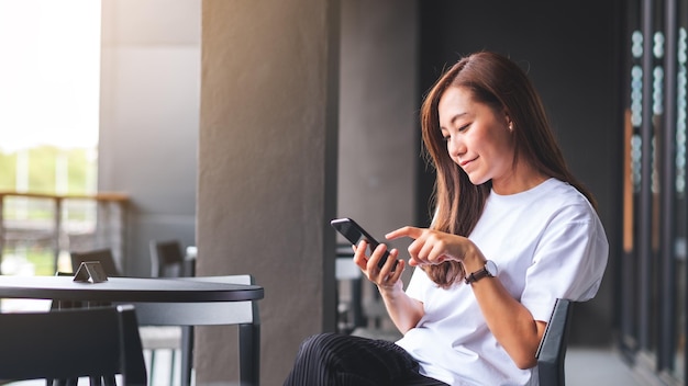 Foto uma bela jovem asiática segurando e usando telefone celular