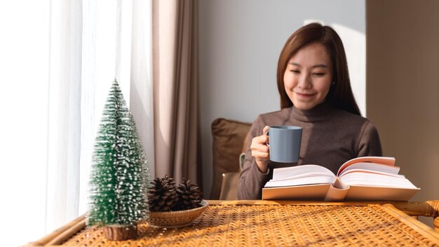 Uma bela jovem asiática tomando café enquanto lê o livro em casa