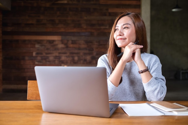 Uma bela jovem asiática usando e trabalhando no computador portátil