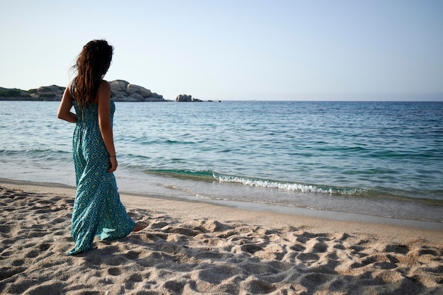 Uma bela jovem caminhando na praia com um vestido azul