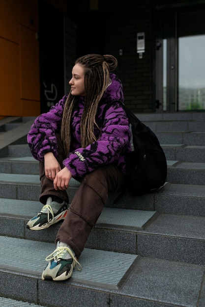 Foto uma bela jovem com dreadlocks e piercings caminha pela cidade.