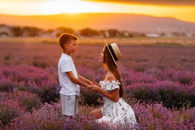 Uma bela jovem com seu filho está caminhando por um belo campo de lavanda e apreciando a fragrância das flores. Descanse e bela natureza. Unidade com a natureza e harmonia.