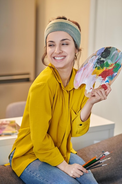 Uma bela jovem com uma paleta e pincéis nas mãos