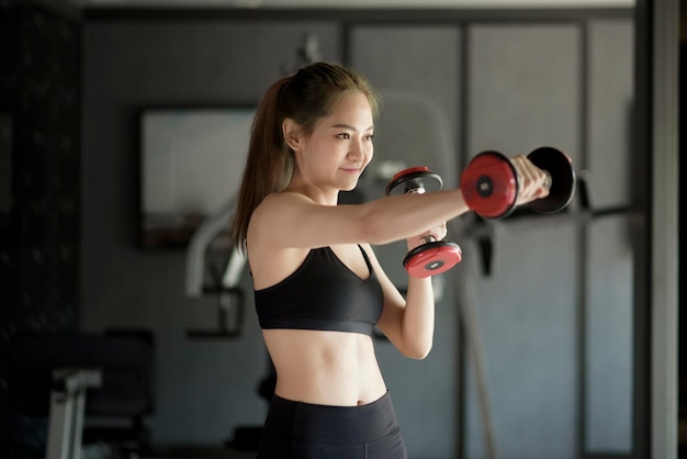 Uma bela jovem em roupas esportivas se exercitando com halteres na academia, conceito de estilo de vida saudável, esportes, treinamento, bem-estar e esporte