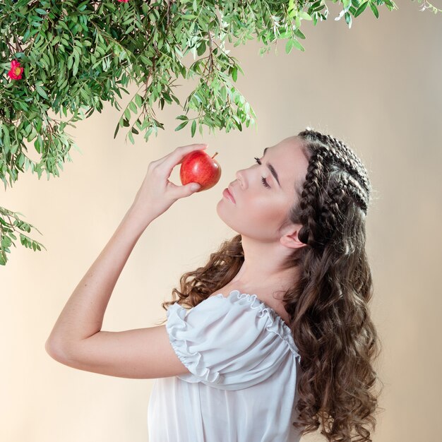 Uma bela jovem no jardim do Éden prova uma fruta madura