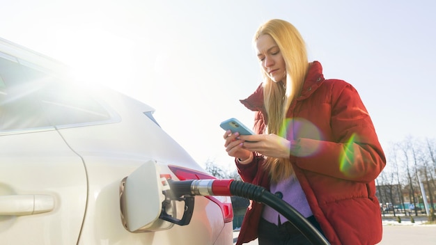 Uma bela jovem paga por um posto de gasolina usando um aplicativo em seu telefone