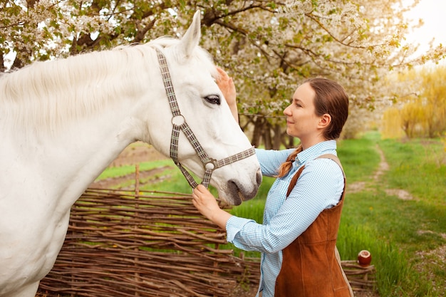 Uma bela jovem posa ao lado de um cavalo branco