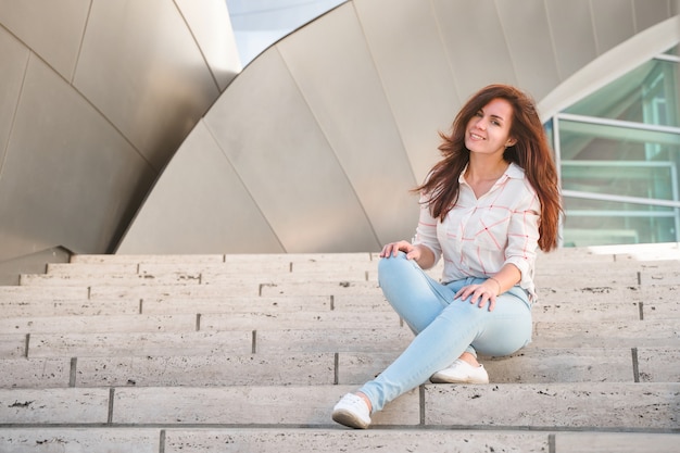 Uma bela jovem sentada na escadaria do Walt Disney Concert Hall em Los Angeles