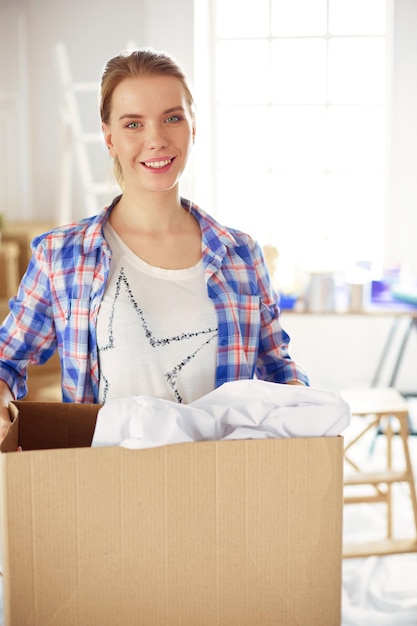 Uma bela jovem solteira desempacotando caixas e se mudando para uma nova casa