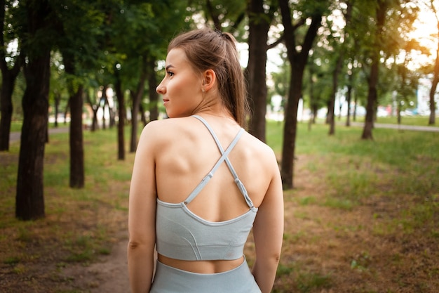 Uma bela jovem, uma vista de trás. corpo musculoso treinado, estilo de vida saudável. ao ar livre, parque, ar fresco. exercite-se na natureza. ginástica. ombros de alívio