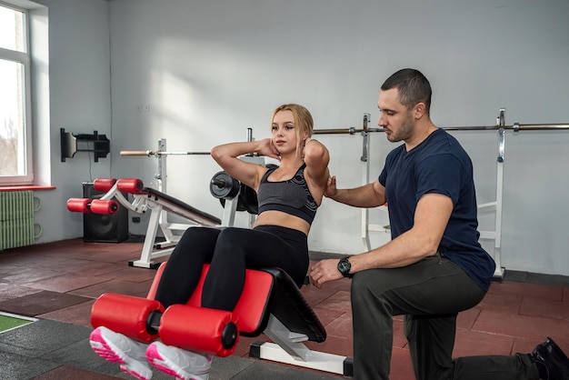 Uma bela jovem veio ao ginásio para fazer um abdominal de um treinador qualificado. O conceito de treinamento no salão com um treinador