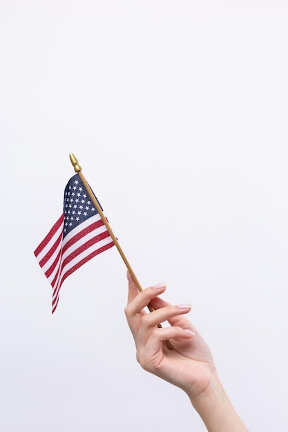 Uma bela mão feminina segura uma bandeira americana em um fundo branco