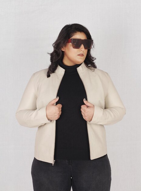 Foto uma bela modelo feminina de tamanho maior posando em jaqueta de couro bege e top preto com saltos altos