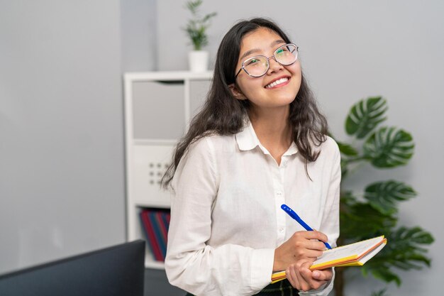 Uma bela morena de óculos está sentada em uma mesa em um escritório da empresa