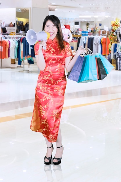 Uma bela mulher asiática a anunciar algo no centro comercial.