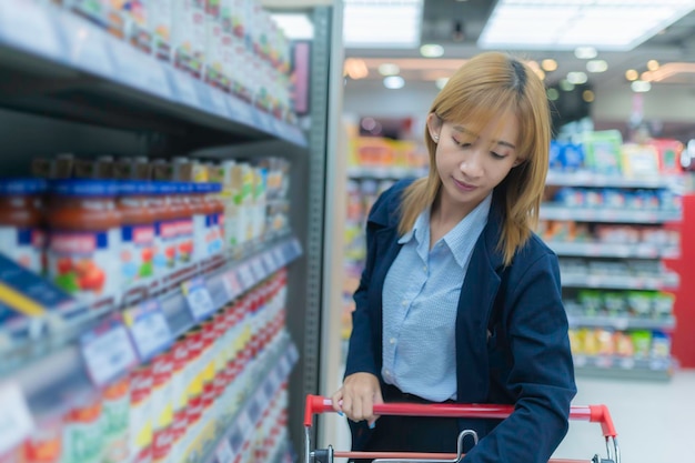 Uma bela mulher asiática a fazer compras com um carrinho no supermercado.