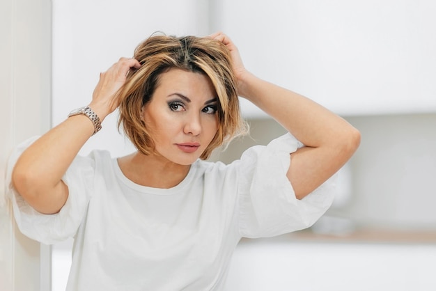 Foto uma bela mulher com uma camiseta branca prepara-se para um encontro endireita o cabelo cabelo mock-up close-up